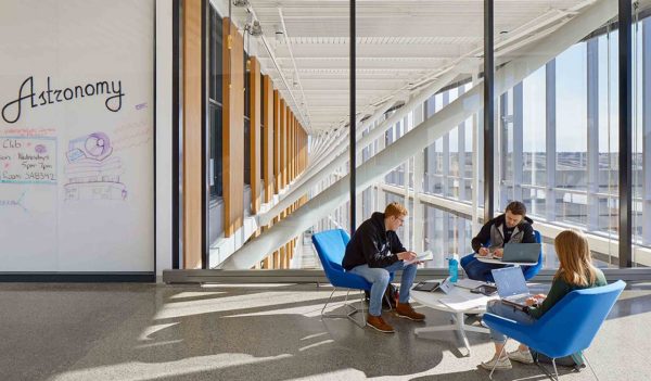 Students studying at a table near a large window.