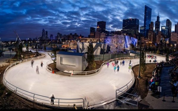 People ice skating at night with the Chicago skyline in the background