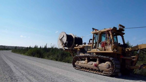 Caterpillar with a large spool of cable being strung