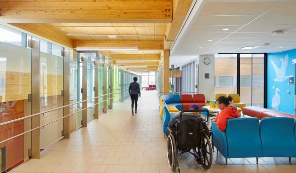 Corridor with waiting area and colored glass walls to rooms