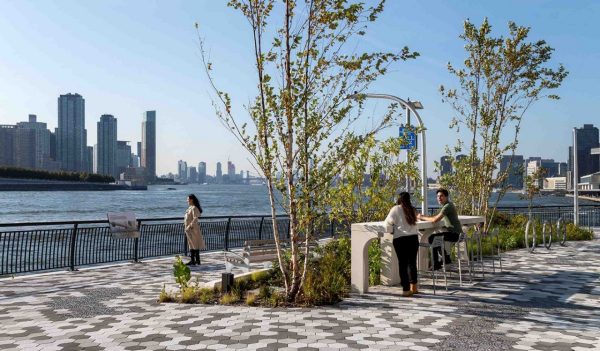 People along the walkway with signage, seating, and plantings