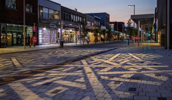 A plaza with retail on each side lit up at night