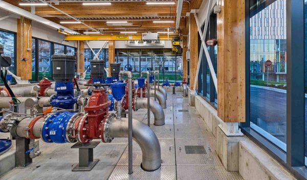 Interior of mechanical room with pipes, surrounded by windows.