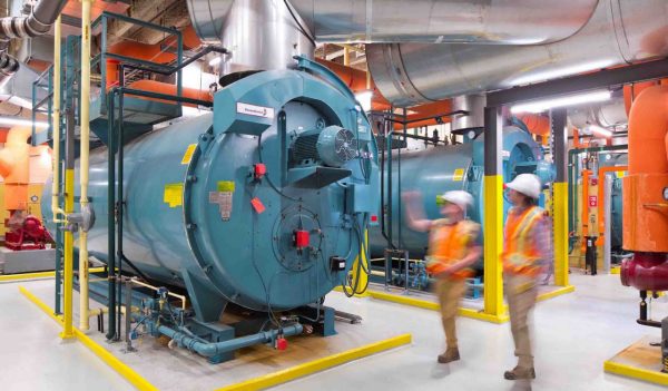 People looking at a generator in the mechanical room.