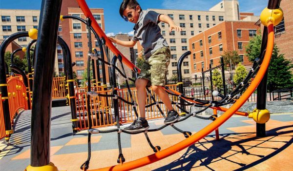 Child playing climbing equipment at park.