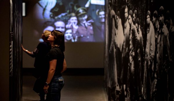 People walking through exhibit area featuring images on the walls.