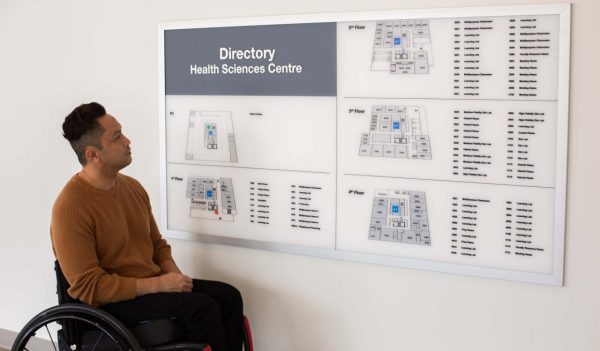 Man in a wheelchair looking at the building directory.