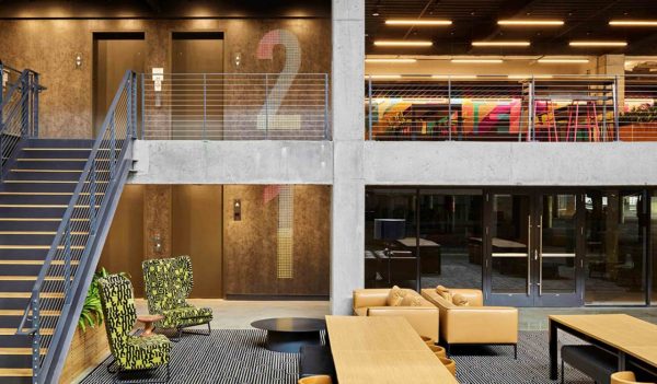 View of two elevations of an office - sitting area on bottom  level and tables and chairs on the top level.