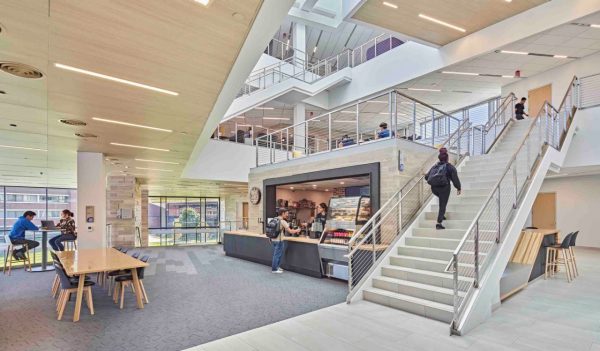 Interior view of common area with staircase, food kiosk and tables.