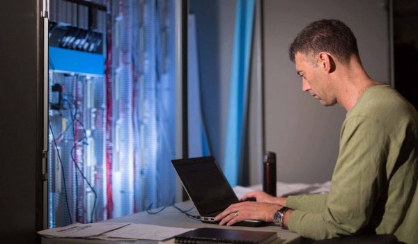 Man working on laptop computer in a data room.