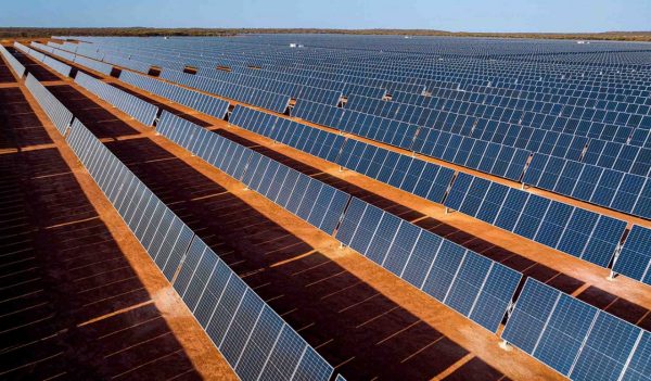 Close-up of rows of solar panels in Australia with the red earth showing through.