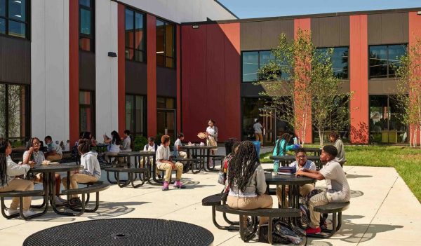 Students sitting at tables in an outdoor courtyard area of the school.