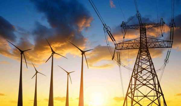 High voltage tower and wind turbines against the sunset