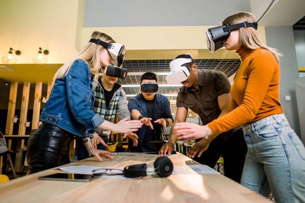 Business people using virtual reality goggles during meeting. Team of multiethnical developers testing virtual reality headset and discussing new ideas to improve the visual experience