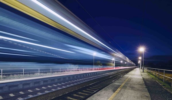 Light trails of passenger train commuting to railroad station at night.